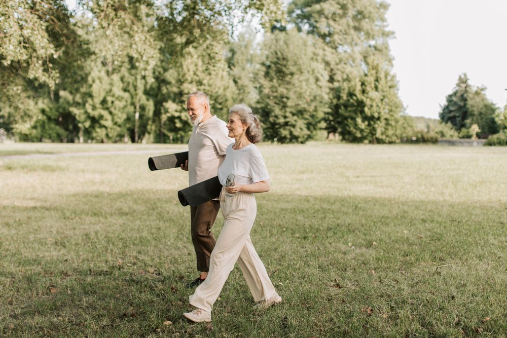 An older couple walking outdoors with an exercise mat, staying active to keep their bones strong