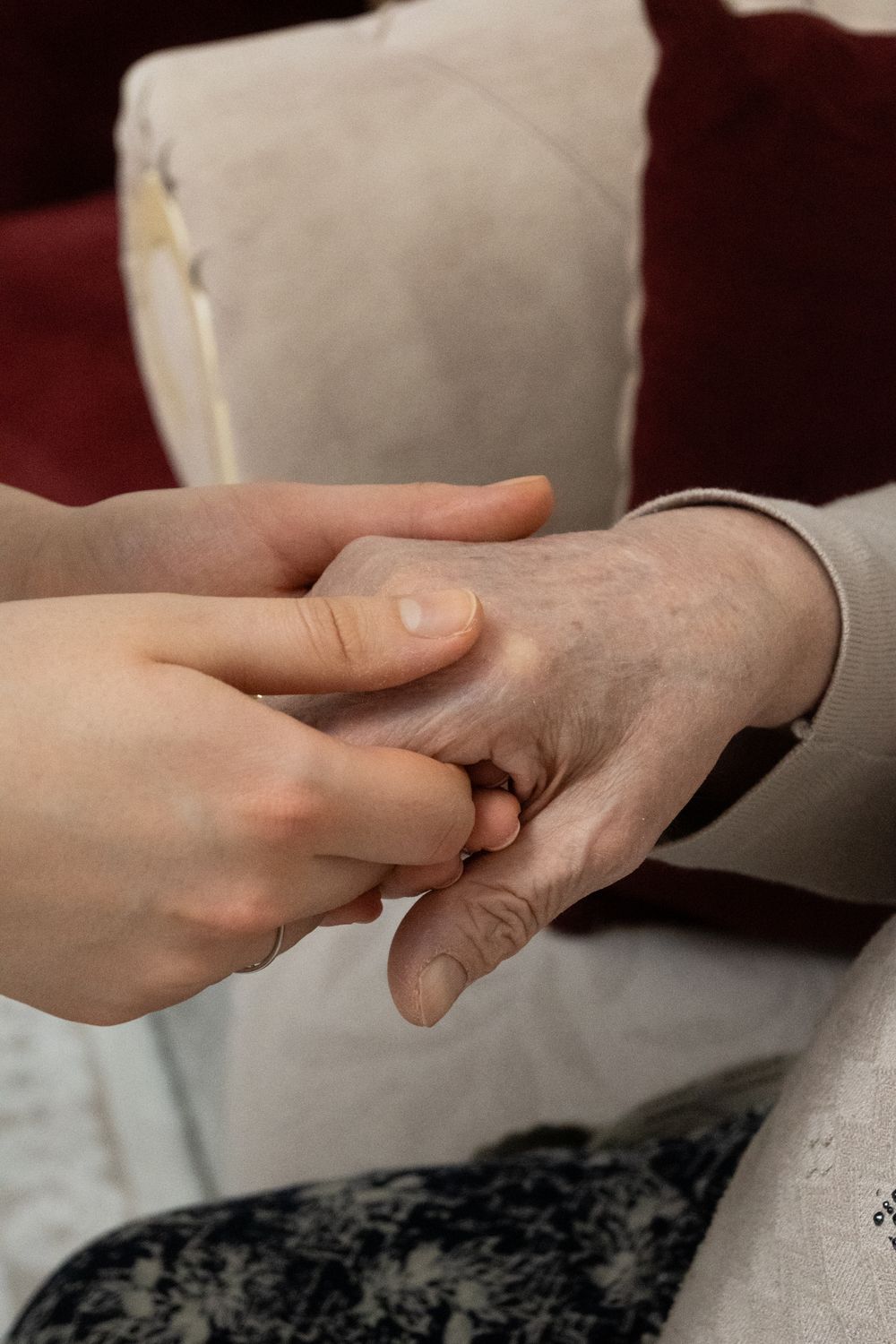 An adult child's hand resting gently over an older parent's hand