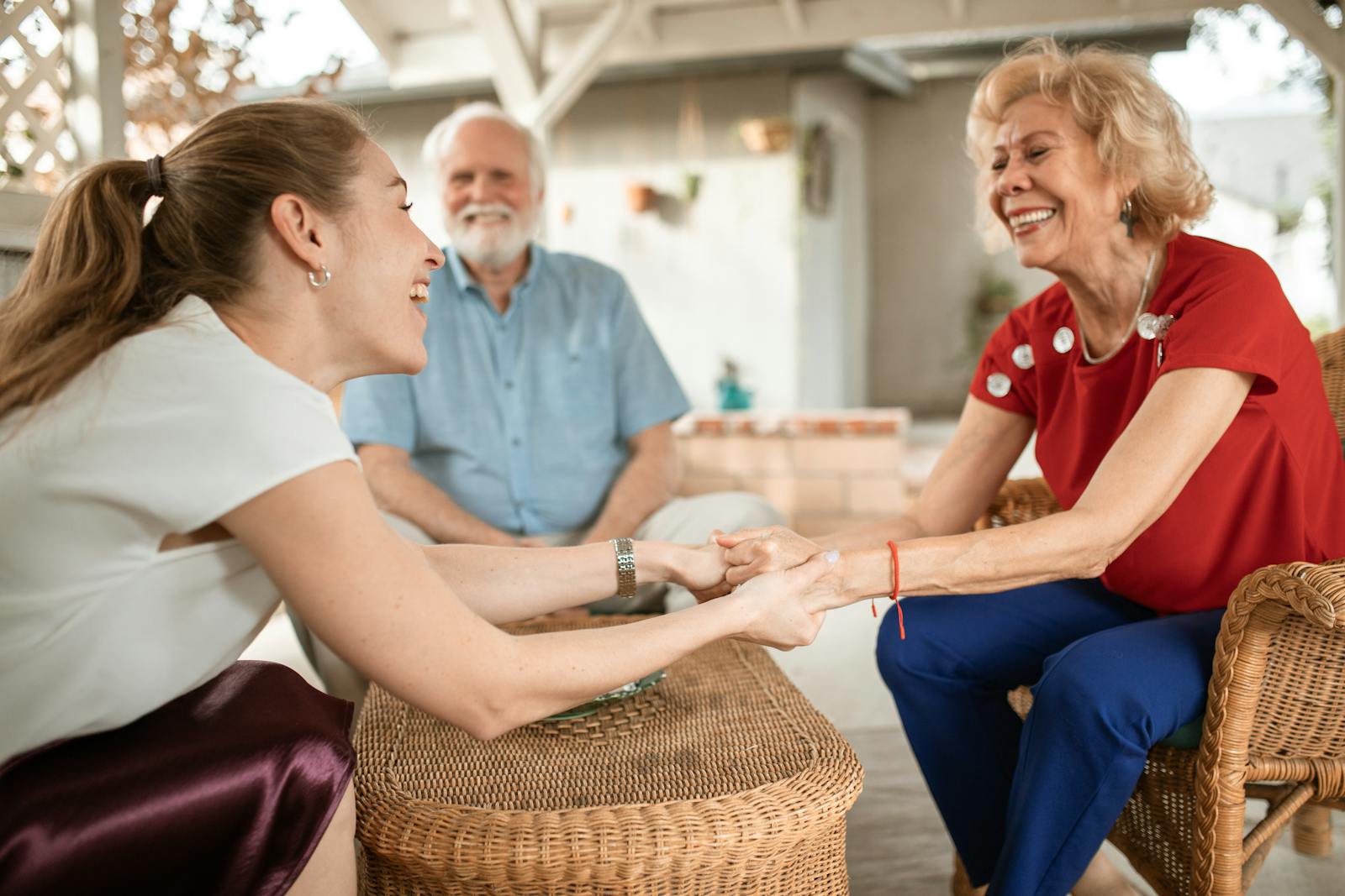 An older woman holding hands and talking warmly with a younger family member who is listening and offering support