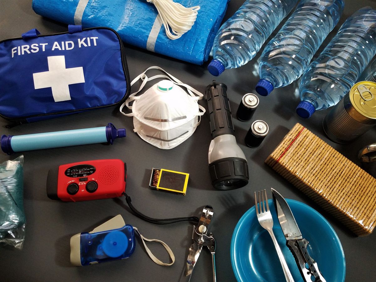 An emergency kit with a flashlight, water, batteries, and a first-aid bag packed and ready on a table