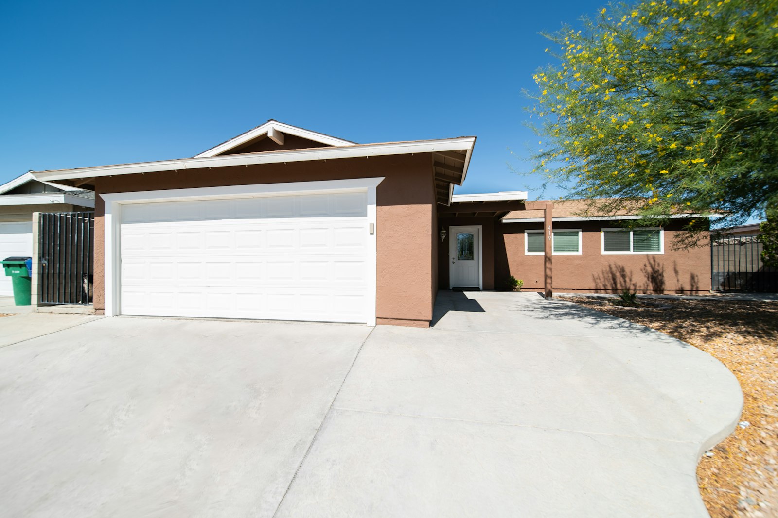 A single-story house with a wide concrete driveway leading to the front door