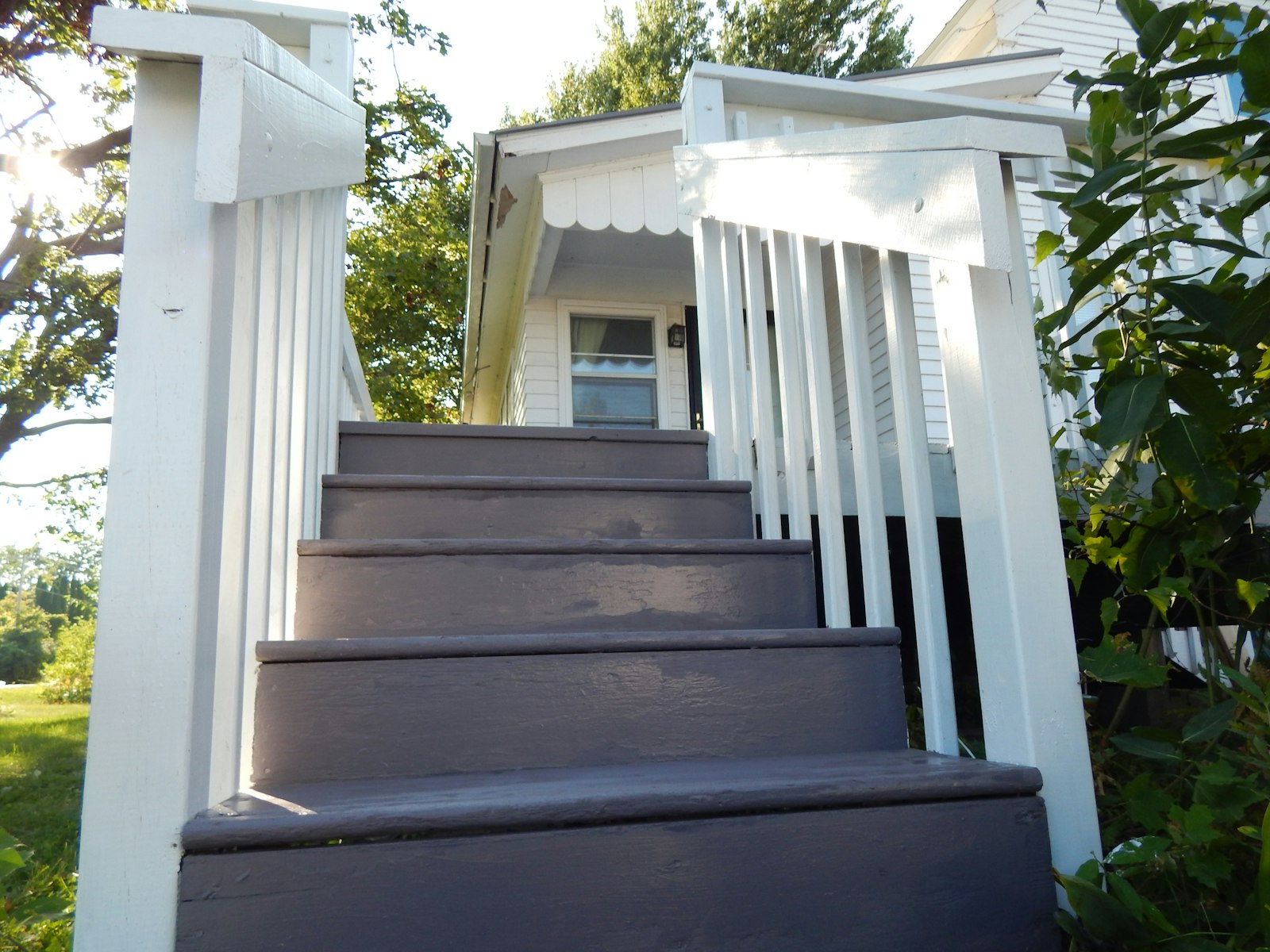 Painted wooden porch steps with white railings leading up to a modest clapboard house