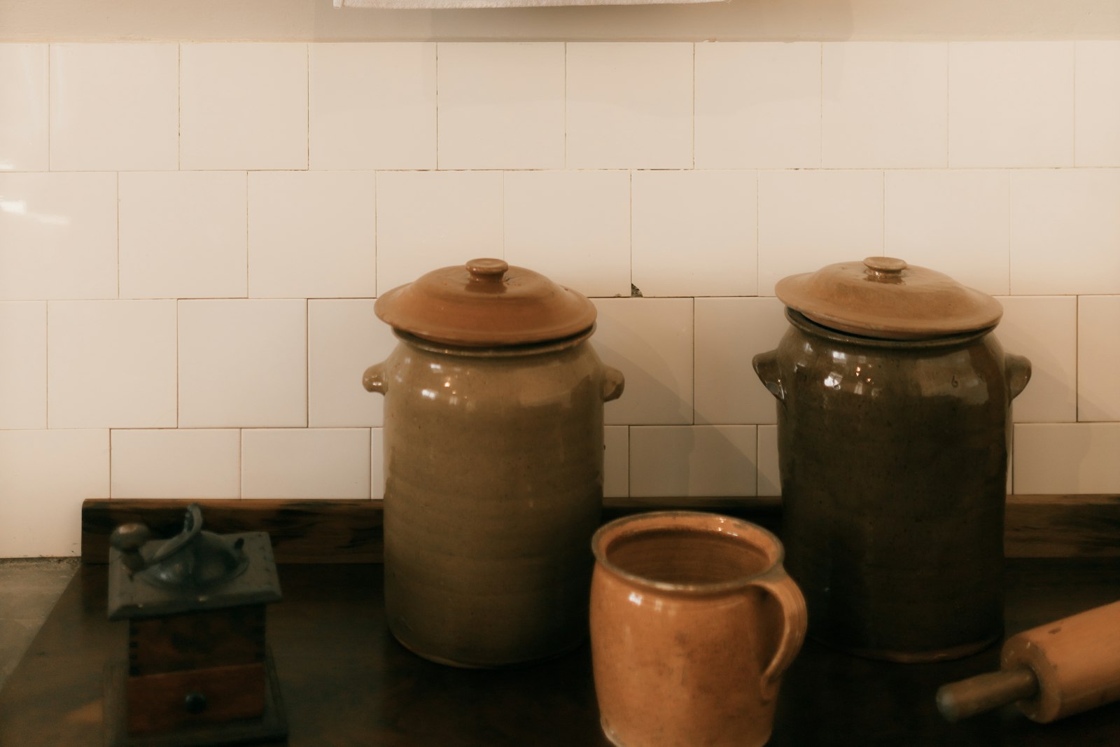 Lidded stoneware crocks, a jug and a rolling pin on a wooden kitchen counter