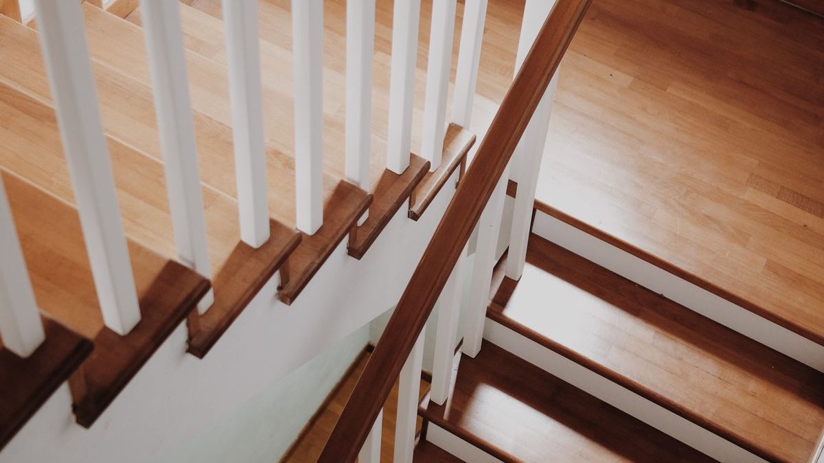 A home staircase with a wooden handrail, the kind a stair lift is fitted to