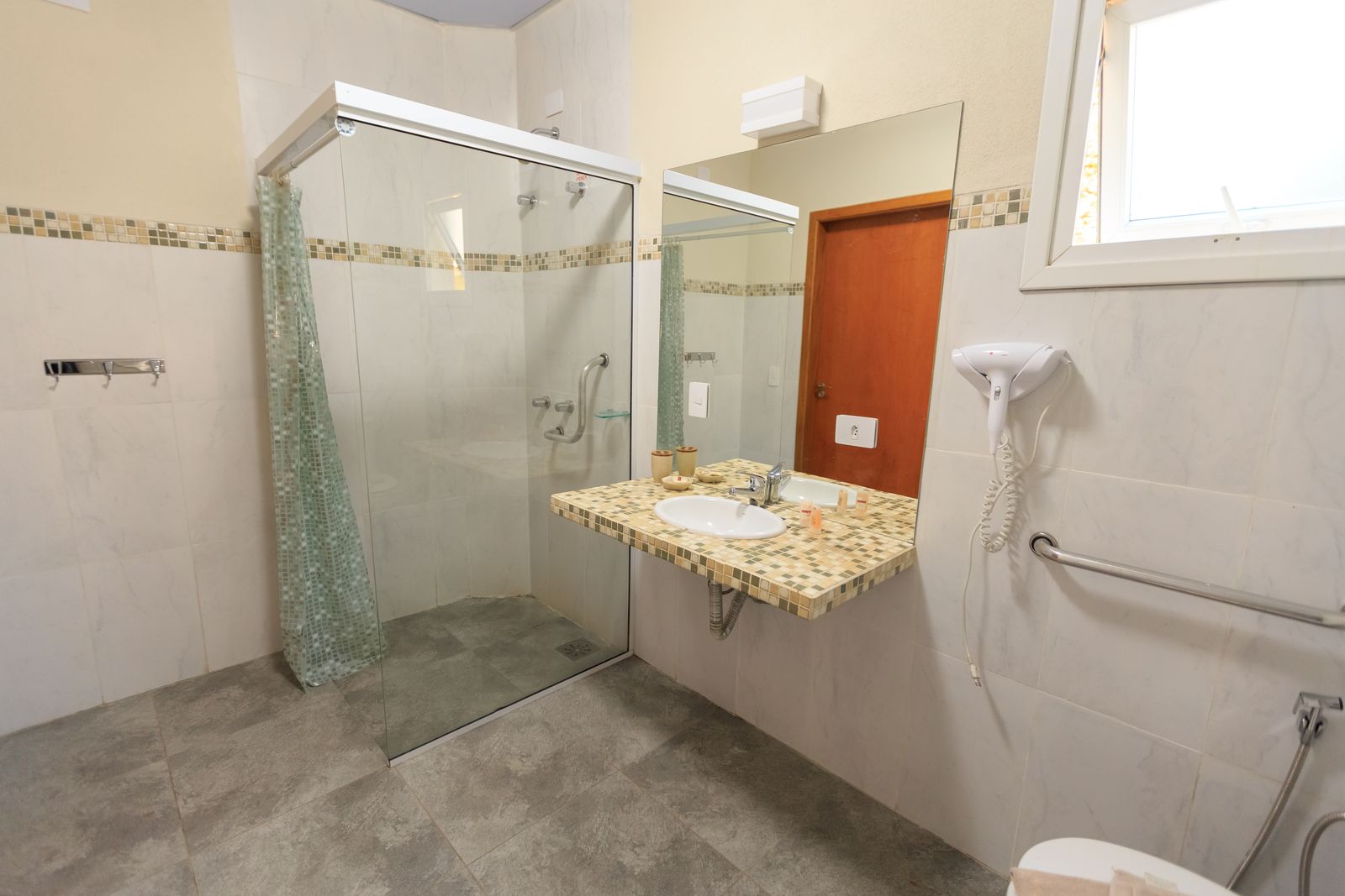 An accessible home bathroom with grab bars and a curbless walk-in shower, set up for safe and dignified bathing