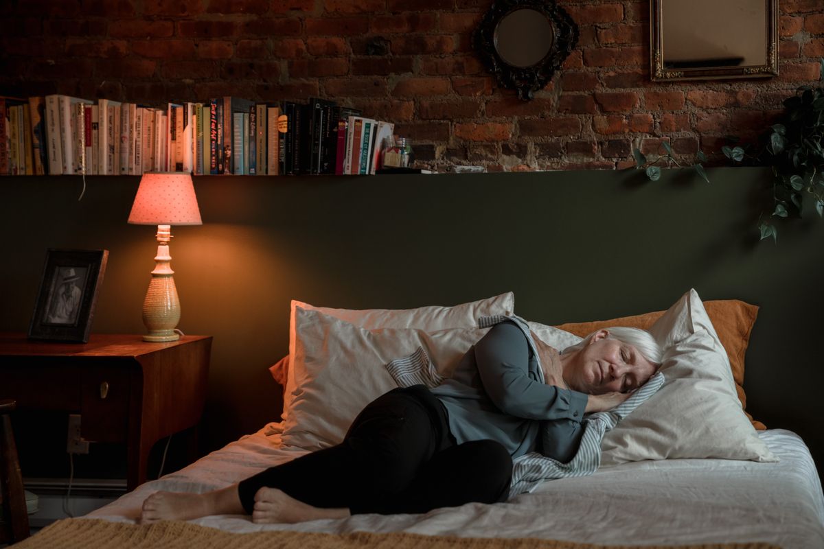 An older woman resting in a warm, softly lit bedroom