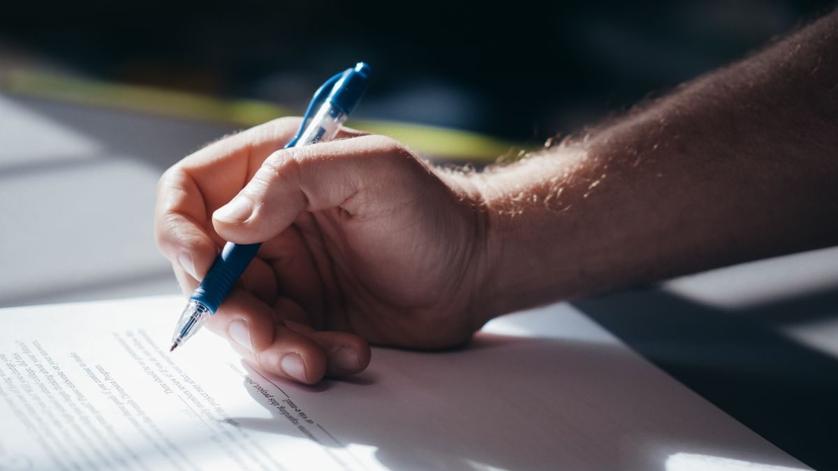 A hand signing an important document with a pen