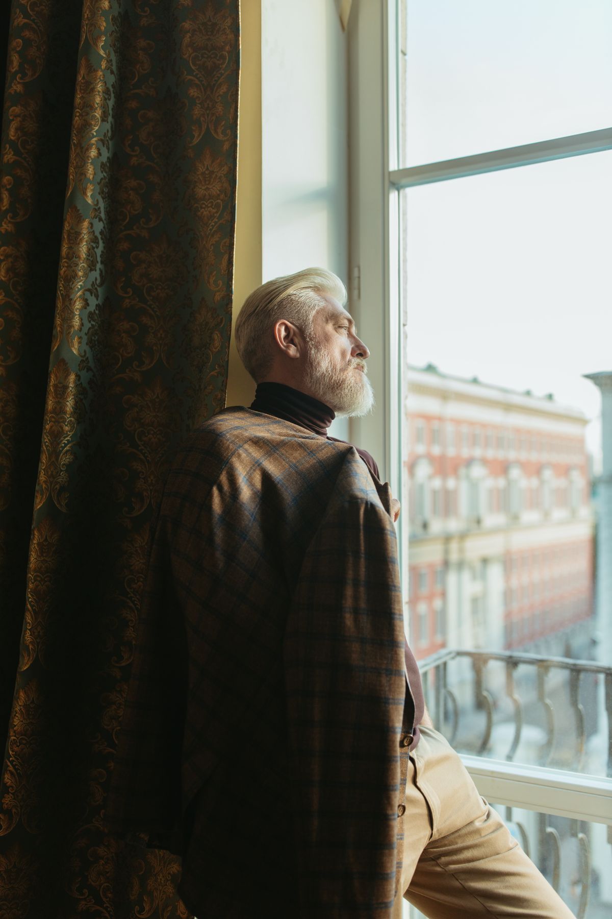 An older man looking thoughtfully out a window