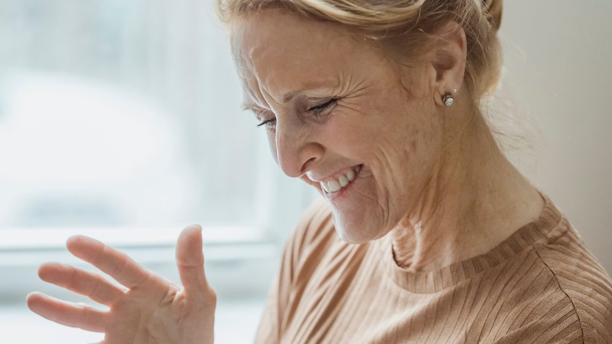 An older woman smiling during a video call with family on a tablet