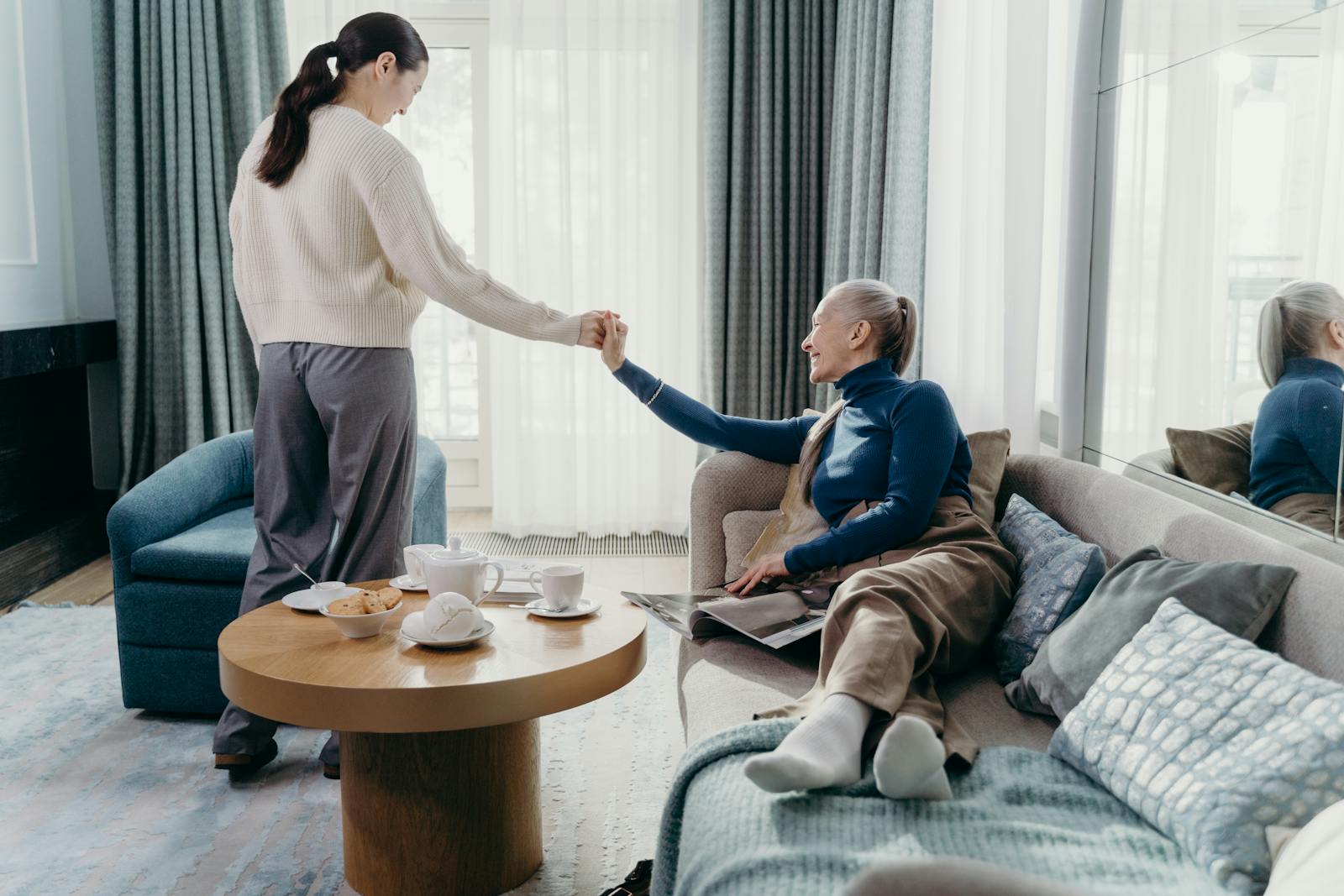 An adult daughter visiting her elderly mother at home, holding her hand warmly