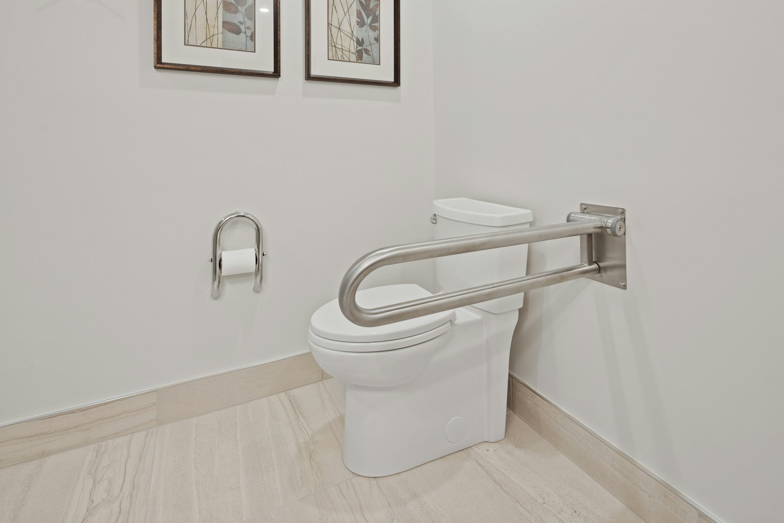 A toilet with a fold-down stainless grab bar mounted on the wall beside it
